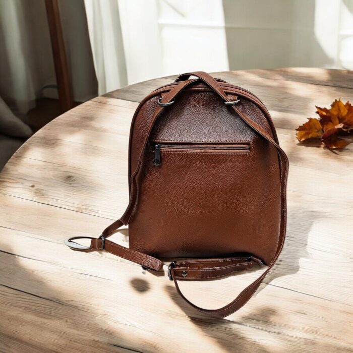 Handmade brown leather backpack with quilted stitching and a front buckle pocket
