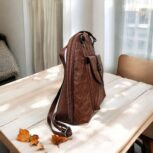Handmade brown leather backpack with quilted stitching and a front buckle pocket
