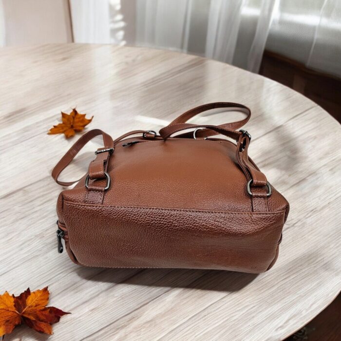 Handmade brown leather backpack with quilted stitching and a front buckle pocket