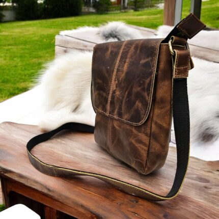 Handmade brown leather crossbody bag featuring a rustic finish, adjustable leather strap, secure flap and zipper closure, and spacious compartments.