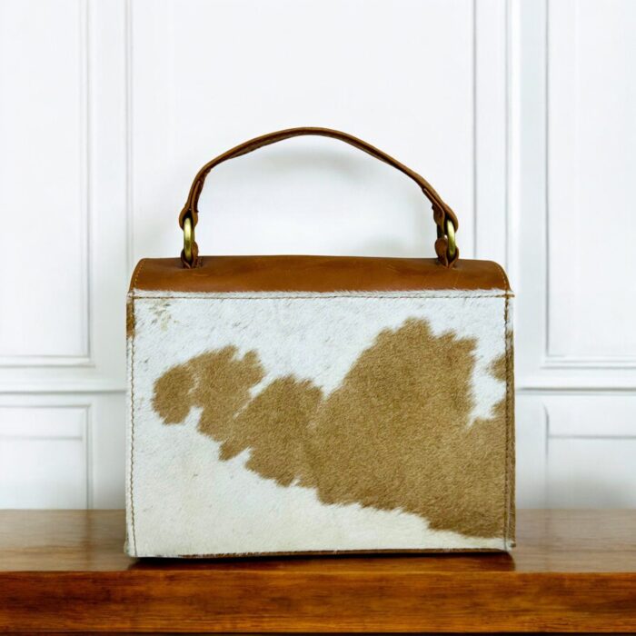 Handcrafted genuine leather handbag with rustic hair-on finish, featuring a sturdy top handle, detachable shoulder strap, and secure twist-lock closure. Elegant and versatile