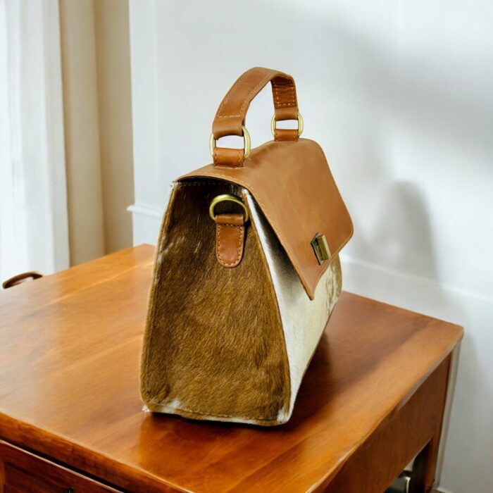 Handcrafted genuine leather handbag with rustic hair-on finish, featuring a sturdy top handle, detachable shoulder strap, and secure twist-lock closure. Elegant and versatile